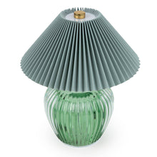 Portable LED table lamp with a chunky ribbed green glass base and a wide pleated grey fabric shade, shown from a closer angle revealing a gold charging detail at the top, photographed on a white background

