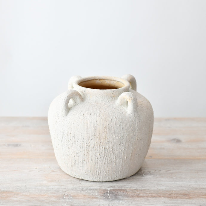 Textured white ceramic vase with small decorative handles and a rounded shape, featuring a rustic stone-effect finish on a wooden surface.